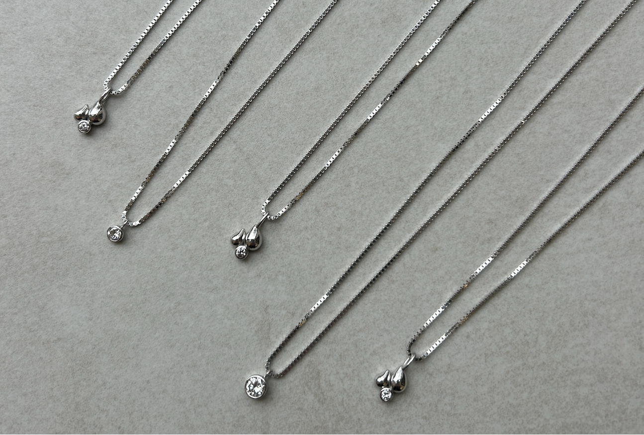 Silver necklaces with small pendants on a gray background