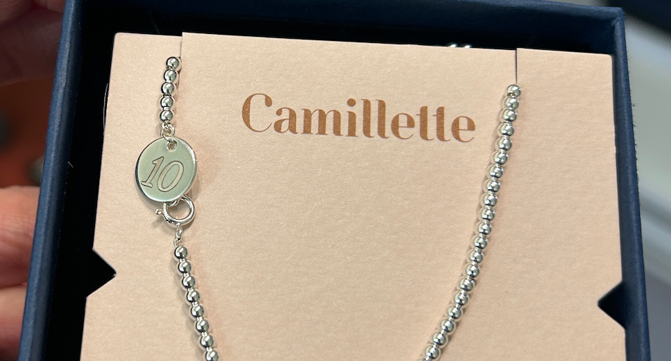 Silver necklace with a round pendant in a 'Camillette' branded box.