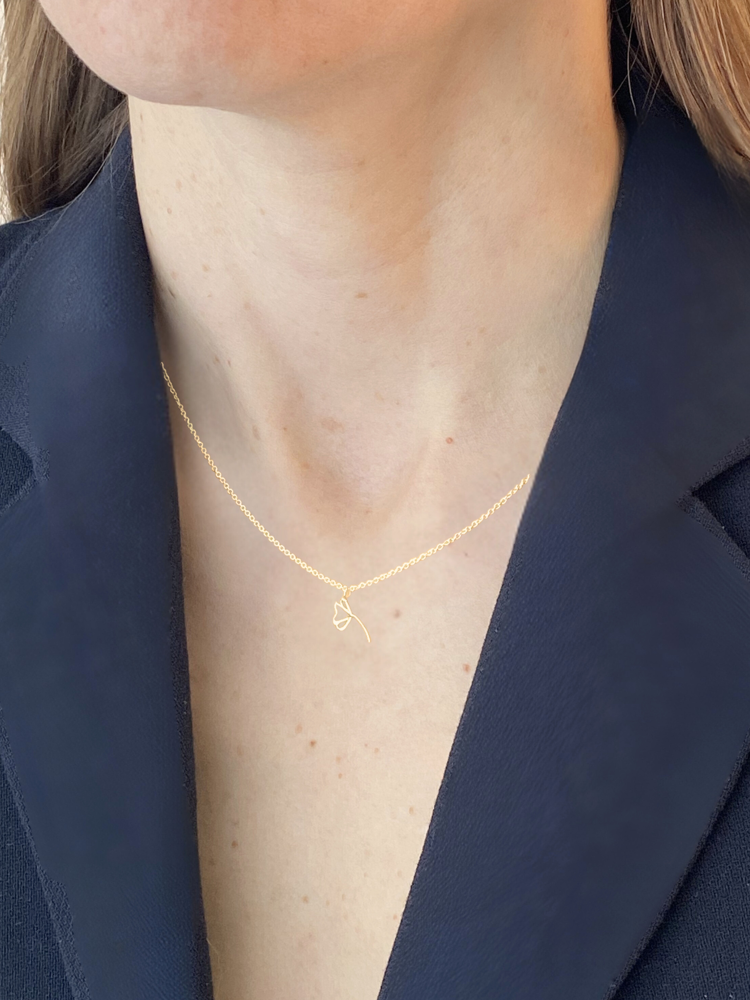 Gold necklace worn by a person with a navy blazer